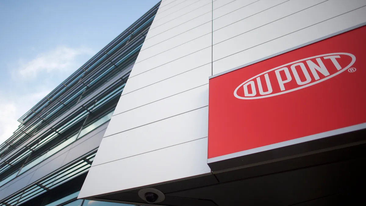 A red DuPont sign on a building's white wall.